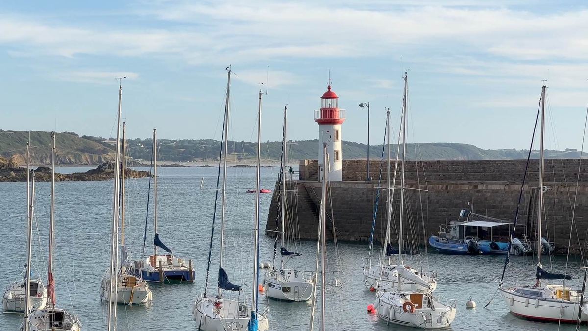 Le port d'Erquy : voiliers au mouillage devant la jetée de pierre et son phare rouge et blanc
